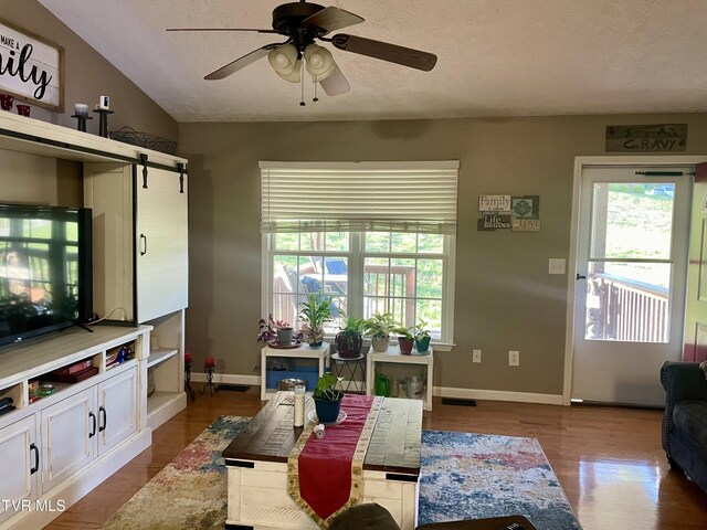 living room featuring a textured ceiling, wood-type flooring, ceiling fan, lofted ceiling, and a barn door