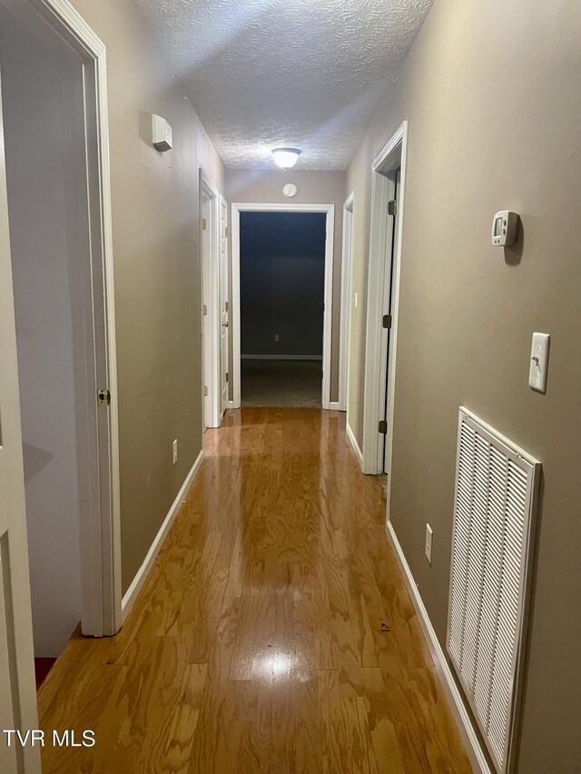 corridor featuring a textured ceiling and wood-type flooring