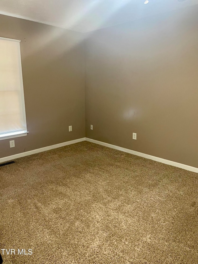 carpeted spare room featuring vaulted ceiling