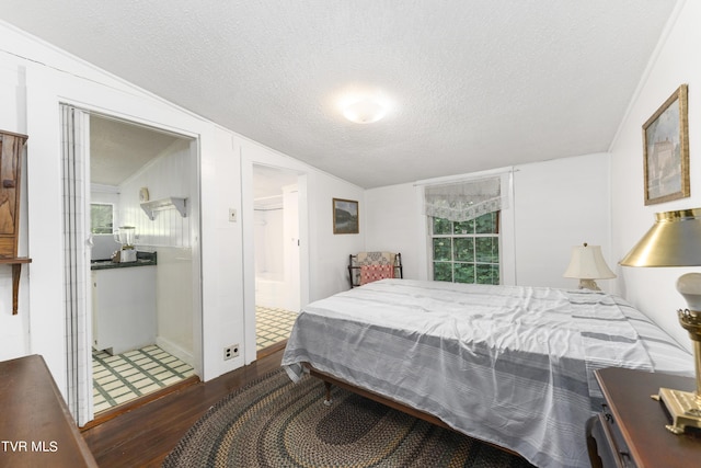 bedroom featuring a textured ceiling, connected bathroom, wood-type flooring, and vaulted ceiling