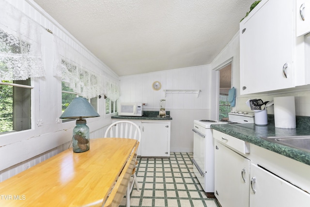 kitchen featuring white cabinets, a textured ceiling, and white appliances