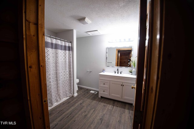 bathroom featuring a textured ceiling, vanity, toilet, and hardwood / wood-style floors