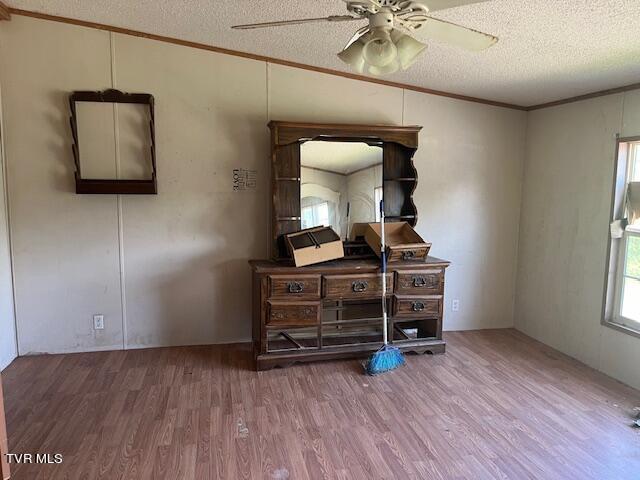 bedroom featuring ceiling fan, a textured ceiling, wood finished floors, and ornamental molding