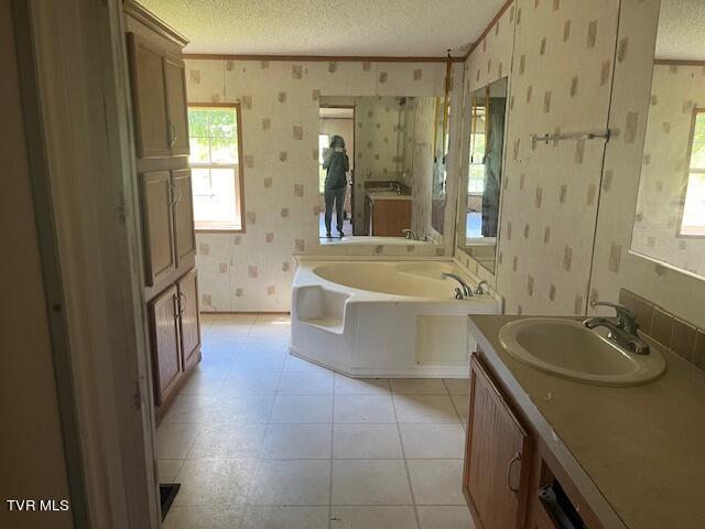 full bathroom featuring tile patterned floors, a garden tub, a textured ceiling, wallpapered walls, and vanity