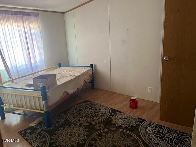 bedroom with wood finished floors and ornamental molding