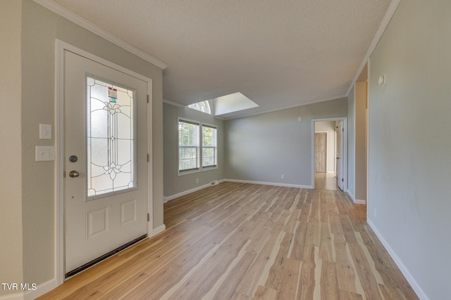 entryway featuring a skylight, light hardwood / wood-style floors, a textured ceiling, and ornamental molding