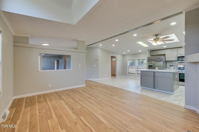 kitchen with gray cabinetry, light hardwood / wood-style flooring, stainless steel appliances, ceiling fan, and a textured ceiling