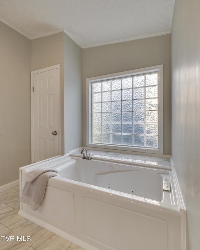 bathroom featuring a bath, ornamental molding, and a textured ceiling