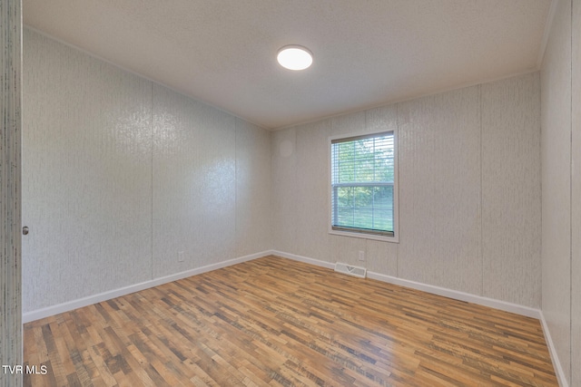 empty room featuring wood-type flooring and a textured ceiling