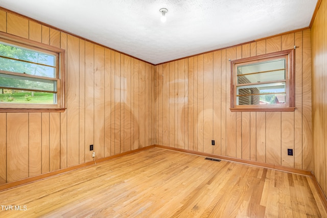 unfurnished room with wood-type flooring, wooden walls, and a textured ceiling