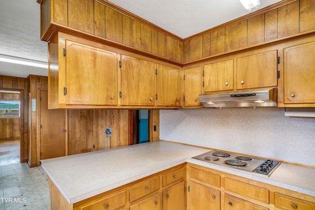 kitchen featuring ornamental molding, stainless steel gas cooktop, wood walls, and a textured ceiling