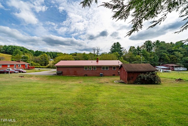 rear view of property featuring a storage unit and a lawn