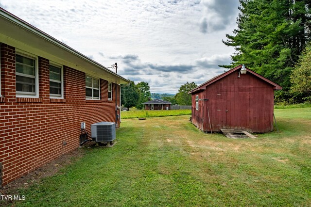 view of yard featuring central AC and a storage unit