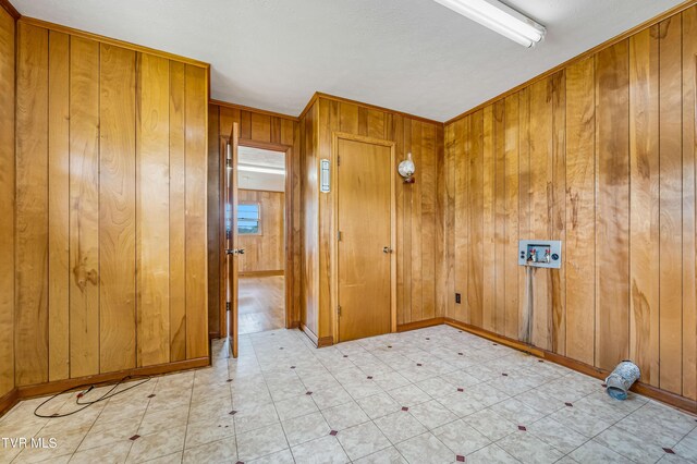 spare room with a textured ceiling, crown molding, and wood walls