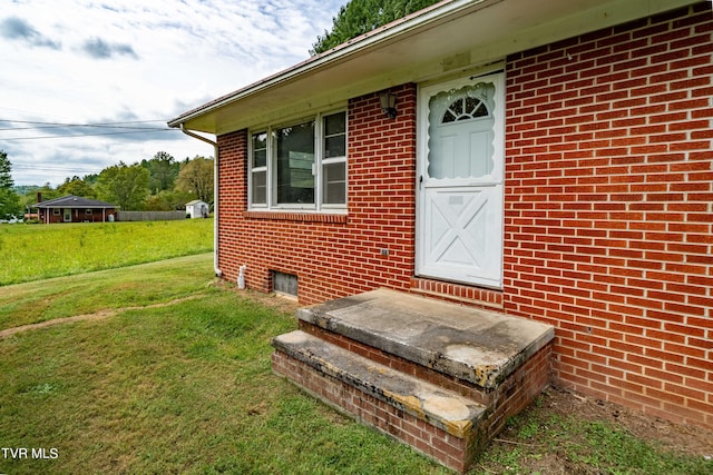 view of exterior entry featuring a lawn