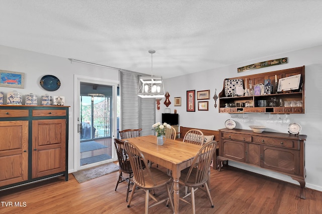 dining room featuring hardwood / wood-style flooring, a notable chandelier, and a textured ceiling