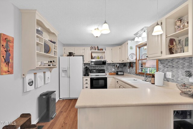 kitchen with white appliances, kitchen peninsula, sink, and hanging light fixtures