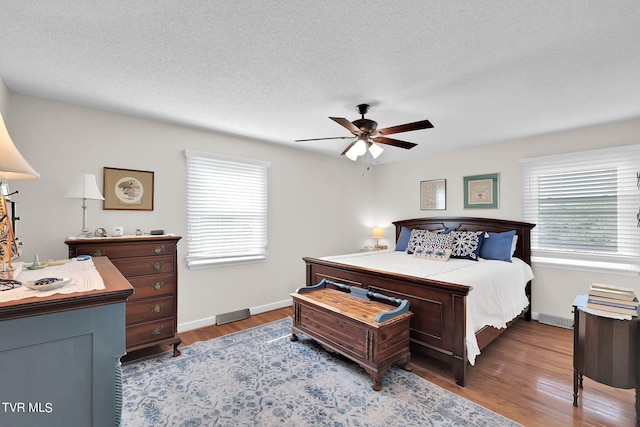 bedroom with a textured ceiling, ceiling fan, and hardwood / wood-style flooring