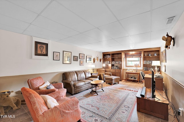 tiled living room with built in shelves and a paneled ceiling