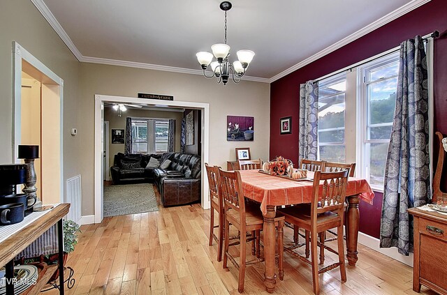 dining space with a notable chandelier, light hardwood / wood-style flooring, ornamental molding, and a healthy amount of sunlight