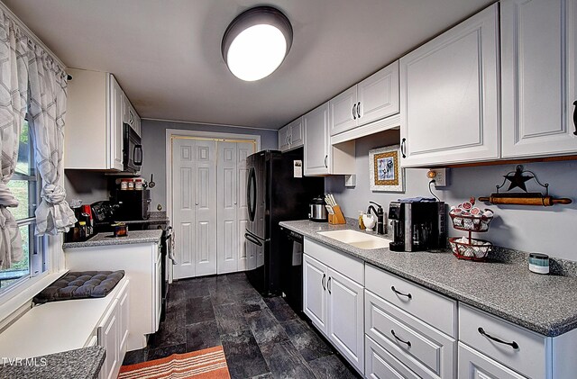 kitchen featuring black appliances, white cabinetry, and sink