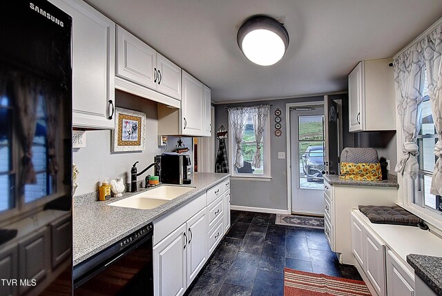 kitchen featuring black dishwasher, sink, and white cabinets