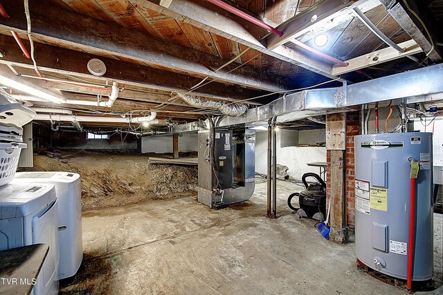 basement featuring washing machine and dryer, heating unit, and electric water heater