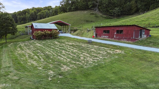 exterior space featuring a front yard, a rural view, and an outbuilding