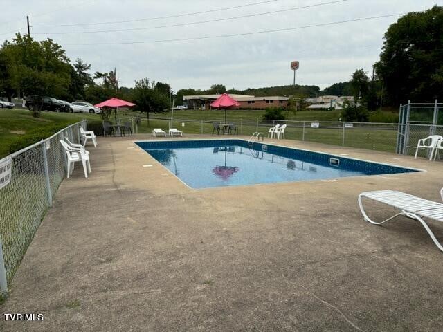 pool featuring a yard, a patio, and fence