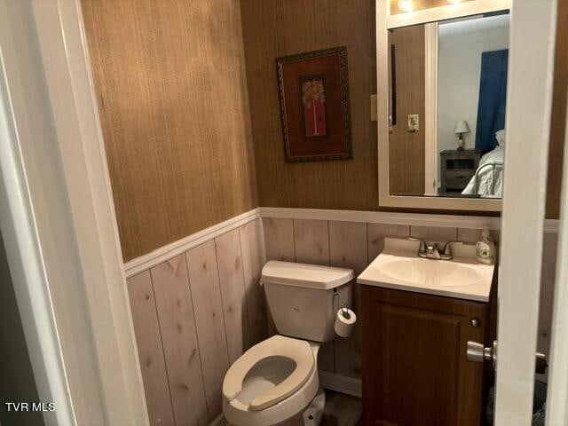 bathroom with toilet, a wainscoted wall, and vanity