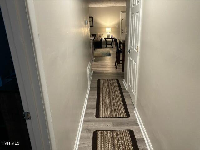 corridor with wood finished floors and baseboards