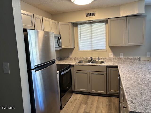 kitchen with a sink, visible vents, light countertops, appliances with stainless steel finishes, and light wood-type flooring