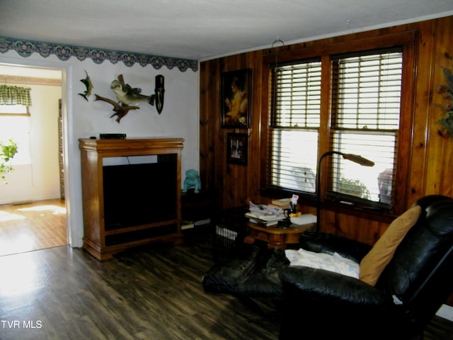 living room with ornamental molding, dark wood-type flooring, and wooden walls