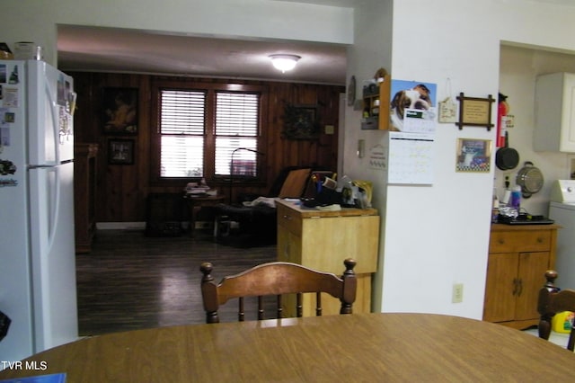 interior space with dark wood-type flooring, white fridge, and wooden walls