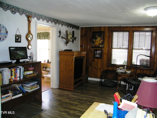 living room with wood walls, dark hardwood / wood-style flooring, and a textured ceiling