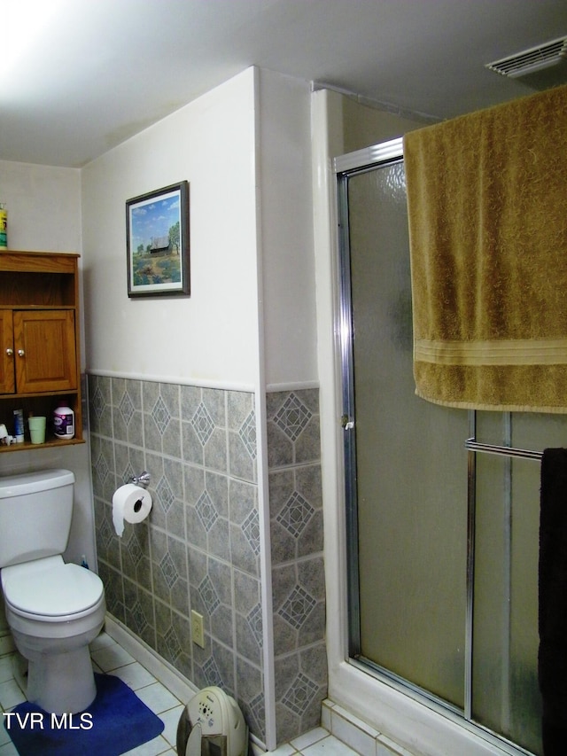 bathroom featuring tile walls, toilet, a shower with door, and tile patterned floors