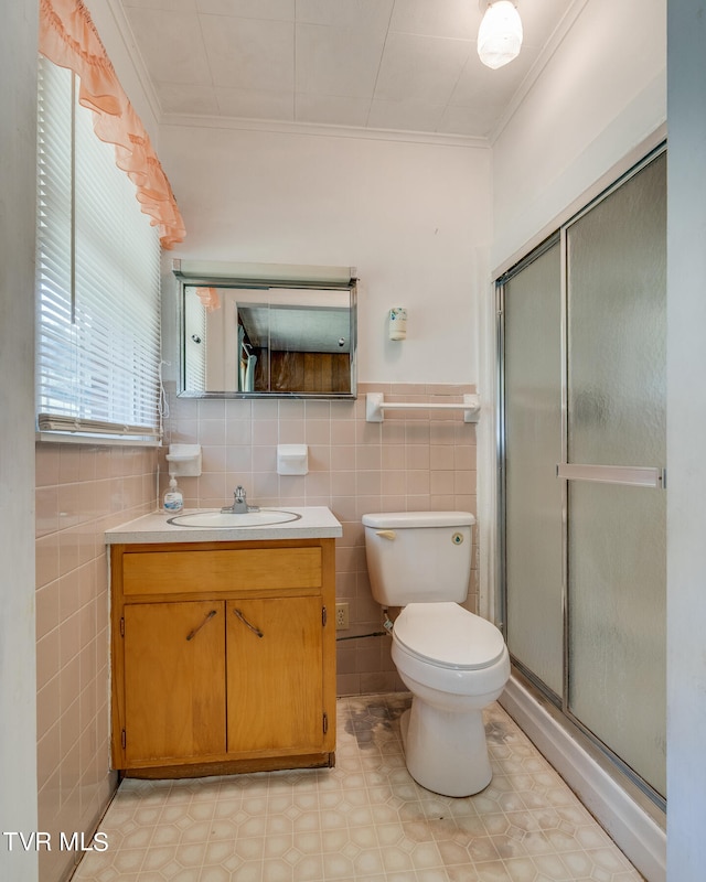 bathroom with a shower with door, toilet, tile walls, vanity, and ornamental molding