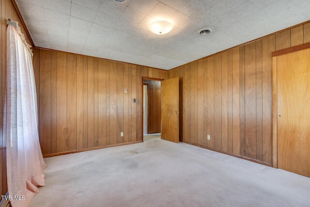 spare room featuring wooden walls and light carpet