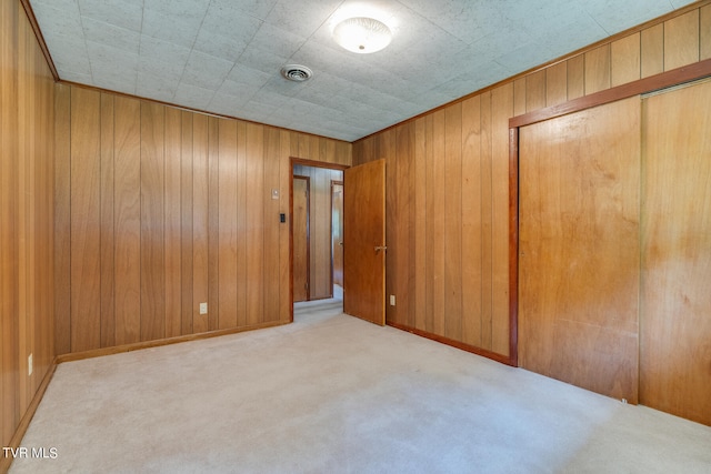 carpeted spare room with wooden walls