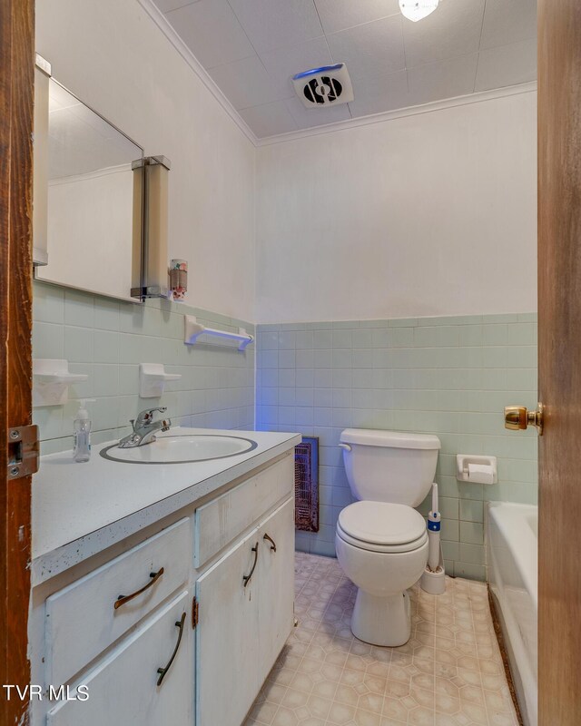 bathroom featuring a tub to relax in, toilet, ornamental molding, tile walls, and vanity