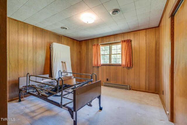 carpeted bedroom with baseboard heating, a closet, and wood walls