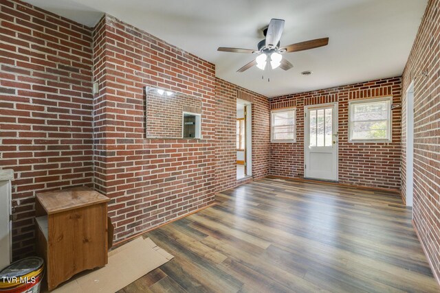 spare room with ceiling fan, dark hardwood / wood-style flooring, and brick wall