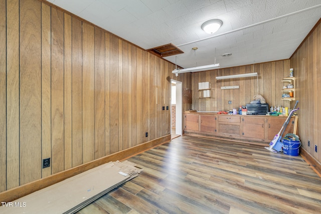 interior space with decorative light fixtures, wood-type flooring, and wooden walls