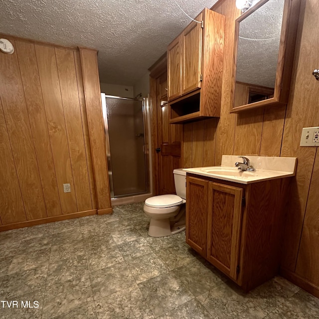 bathroom with wood walls, a shower with door, vanity, and toilet