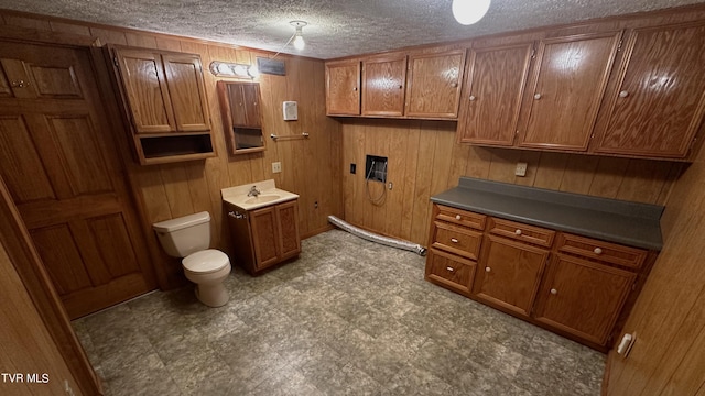 bathroom featuring wooden walls, a textured ceiling, and toilet