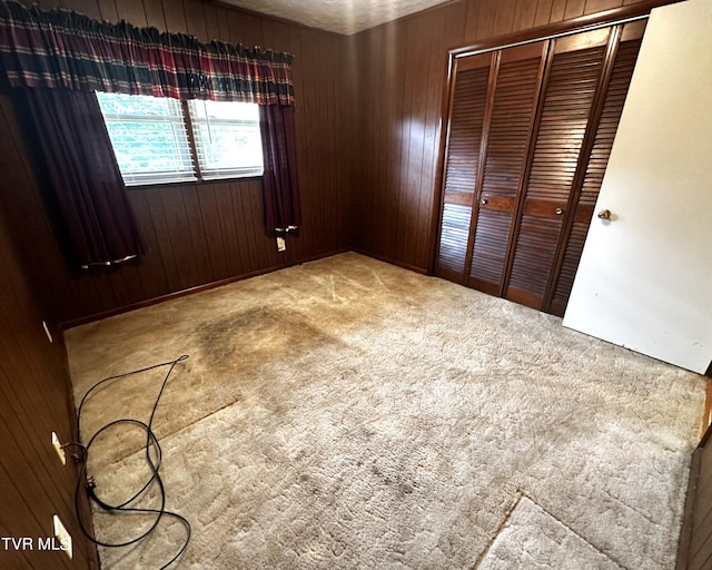 unfurnished bedroom with wood walls, a closet, and carpet floors