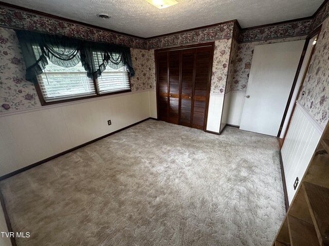 unfurnished bedroom featuring a textured ceiling, carpet, and a closet