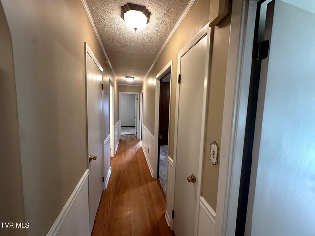 hall with ornamental molding, a textured ceiling, and dark hardwood / wood-style flooring