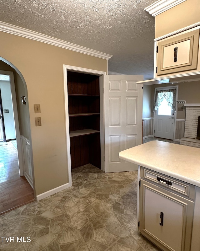 kitchen with a textured ceiling, crown molding, light hardwood / wood-style floors, and built in features