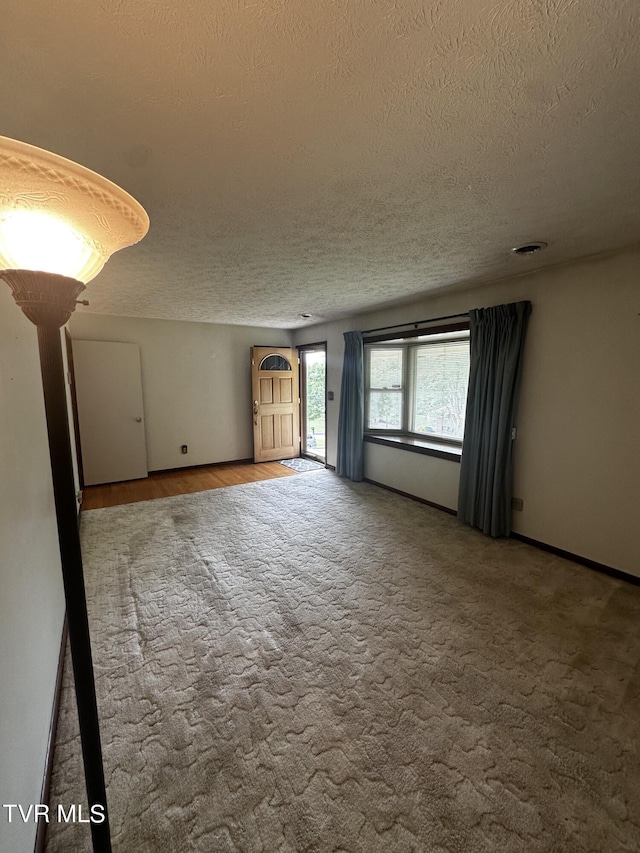 carpeted spare room featuring a textured ceiling